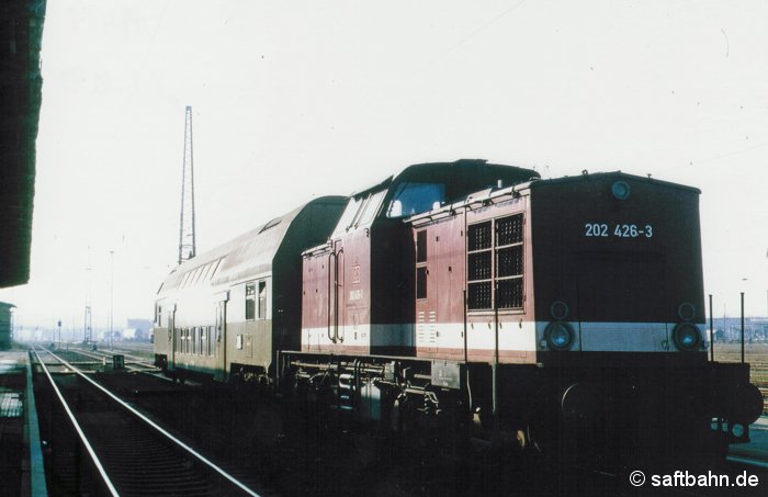Nahverkehrsszenarie am 24.10.1995: Diesellok 202 426-3 ist soeben als Regionalbahn 8128 aus Stumsdorf mit dem Doppelstocksteuerwagen am Bitterfelder Bahnsteig 5 eingefahren und gönnt sich nun eine dreistündige Pause. Die Doppelstocksteuerwagen kamen mit dem Fahrplanwechsel im Mai 1995 auf die Strecke. Das Lokumsetzen in Stumsdorf und Bitterfeld entfiel, sodass die Umsteigemöglichkeiten zu den Anschlusszügen für die Reisenden verbessert werden konnten. 