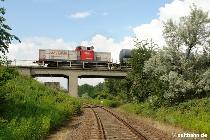 In Bitterfeld Nord überquert  die Schiene der dortigen Chemie- und Werksbahn das Saftbahngleis. Am 02.07.2009 ist V133 der Regiobahn Bitterfeld-Berlin GmbH mit einigen Kesselwagen unterwegs und gelangt durch die Eisenbahnüberführung schnell zu den einzelnen Chemie-Arealen. Bis zur Wende 1989 konnte man noch mit einer Verbindungskurve von Stumsdorf kommend auf die Infrastruktur der Werksbahn fahren. 