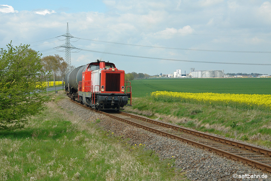 Begleitet von herrlich duftenden Raps fährt V133 am 25.04.2012 aus Zörbig kommend in Großzöberitz ein. Im Hintergrund die Biokraftstoffwerk der Verbio und die etwas weiter weg zu erkennende Zörbiger Stadtkirche Sankt Mauritius. 