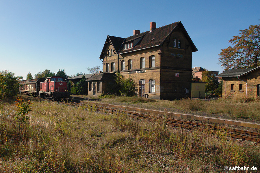 Vorbei am alten; zu diesem Zeitpunkt noch ungenutzten Bahnhofsgebäude von Sandersdorf rollt am 09.10.2009 die WFL V60-Lok ex 346 931 mit Schiebewandwagen vom Zörbiger Bahnhof. Die Lok war zu diesem Zeitpunkt an die Ascherslebener Verkehrsgesellschaft vermietet, welche den Auftrag hatte die Wagen nach Bitterfeld Nord zu überführen. 