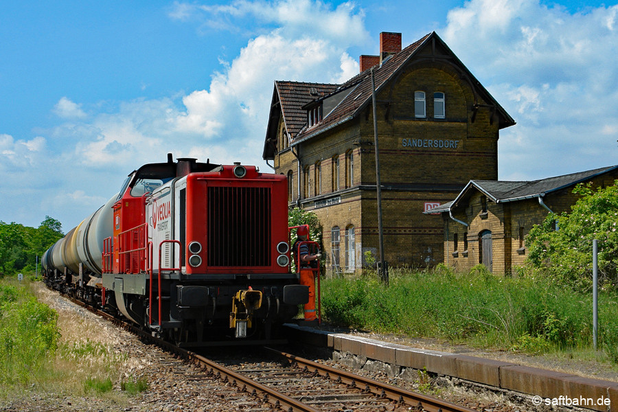 Die Renaissance des Sandersdorfer Bahnhogsgebäudes lies am 07.06.2010 noch auf sich warten, als die Regiobahn Bitterfeld mit Lok V133 und dem Kesselzug aus Zörbig an ihm vorbei fuhr. Obwohl das DB Logo zu dieser Zeit noch die Giebelseite zierte, gehörte das stark verdreckt wirkende Gebäude bereits einer Immobiliengesellschaft. Erst 5 Jahre später konnte ein Käufer für den Bahnhof gefunden werden. 